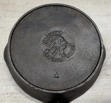 Bottom of Wapak "Indian" number 4 cast iron skillet pan with heat ring. Indian head medallion in centere of bottom of pan. Sold for $625.